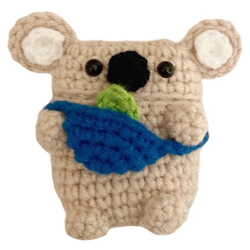 Handmade knitted koala bear backpack cover for Apple Airpods case on a table.