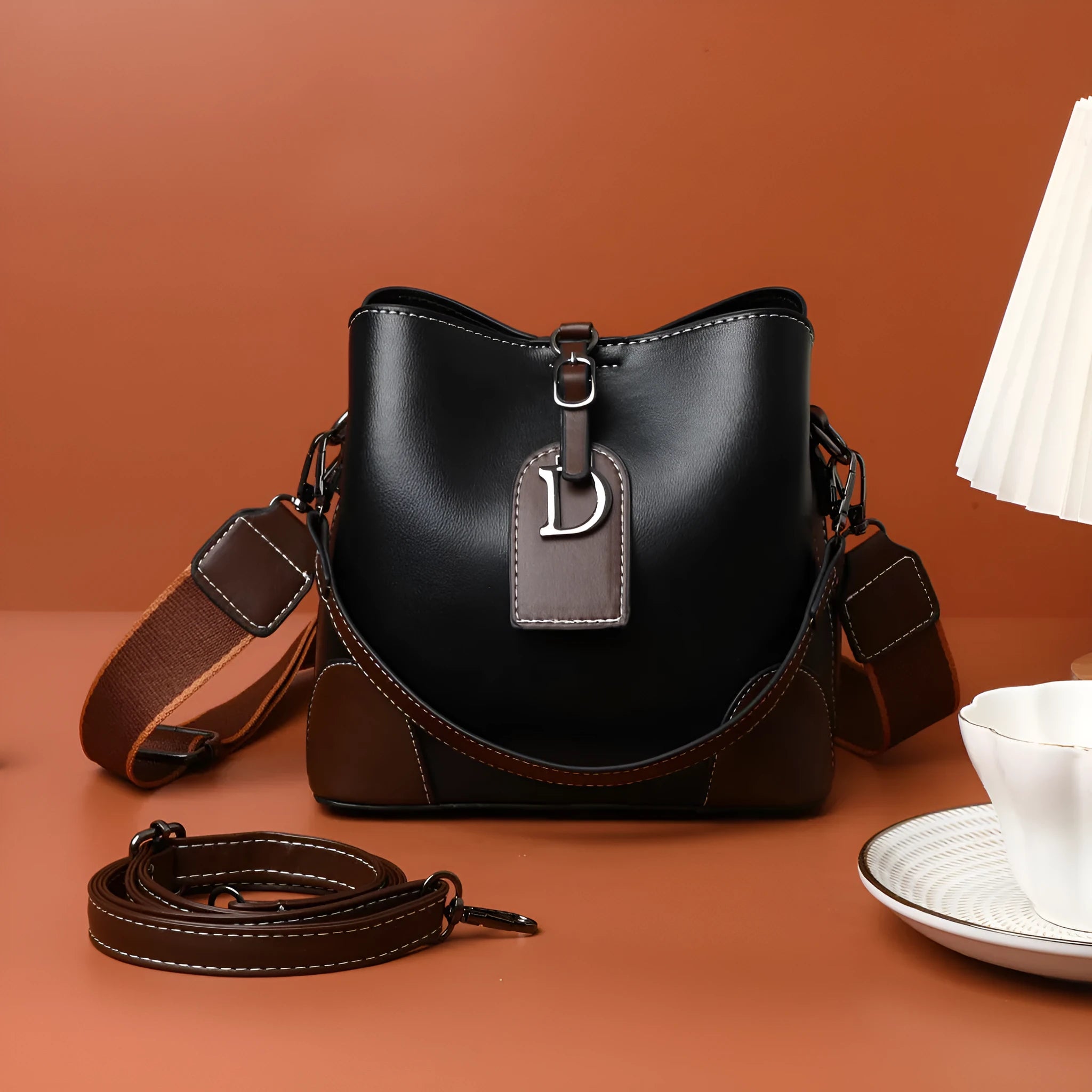 Women's soft PU bucket bag with tassel and contrast colour stitching on a plain background