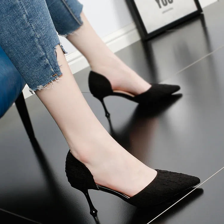 Women's black pointed stiletto high heels with a thin heel on a plain background.