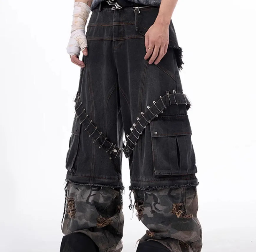 Grey men's jeans with camouflage pattern and spliced construction, showing pin and ribbon details.