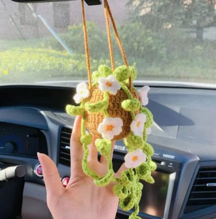Green and white knitted wool car plant decoration with macramé texture and a white hanging rope.