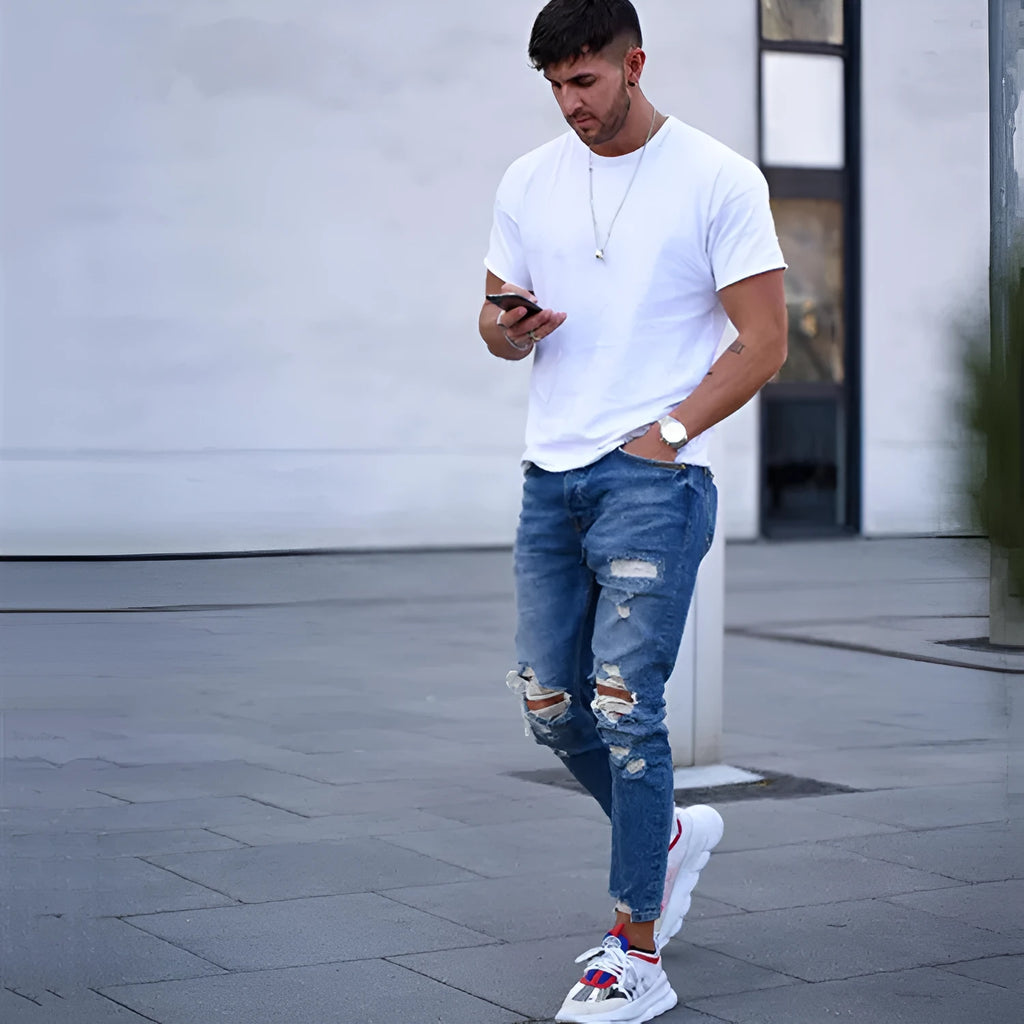 Men's blue jeans with hole detailing showing cotton fabric texture and distressed design