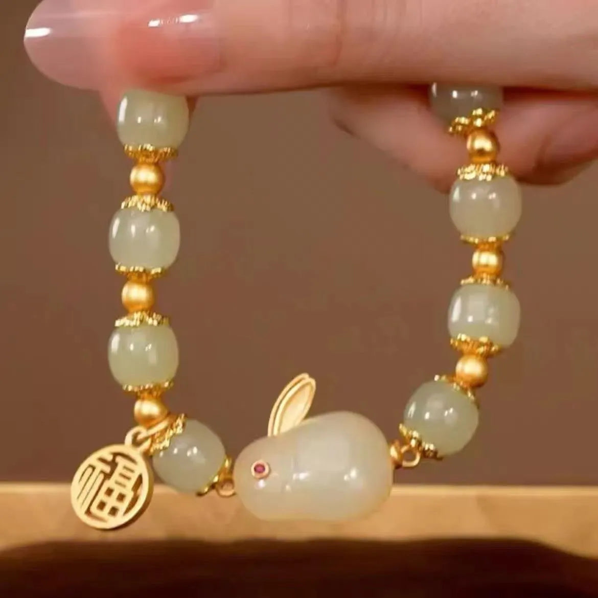 Green jade hare charm bracelet with black hand band showing lily engravings and fu character detail