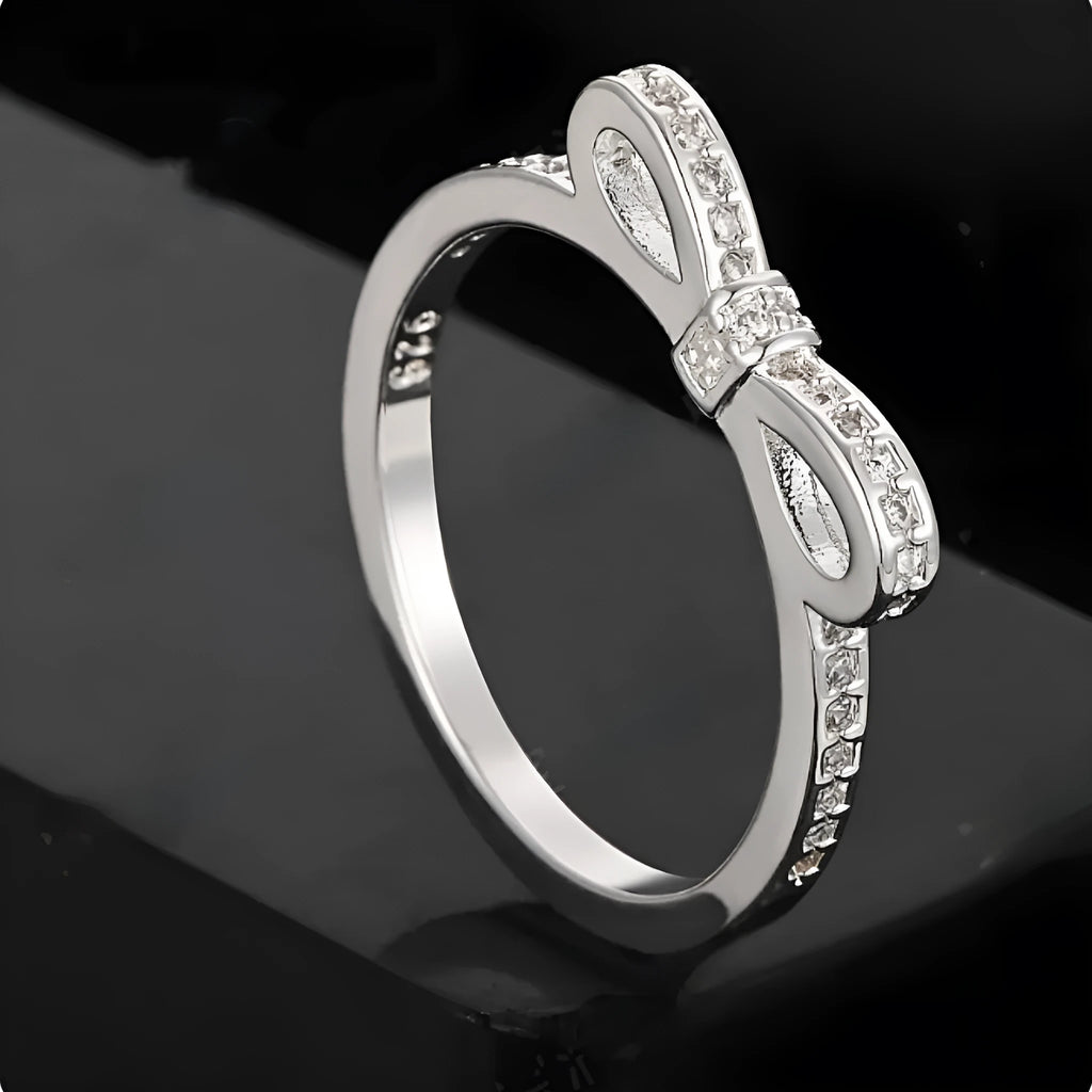 Silver electroplated ring with a detailed bow shape and set zircon crystal accents.