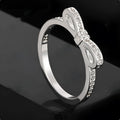 Silver electroplated ring with a detailed bow shape and set zircon crystal accents.
