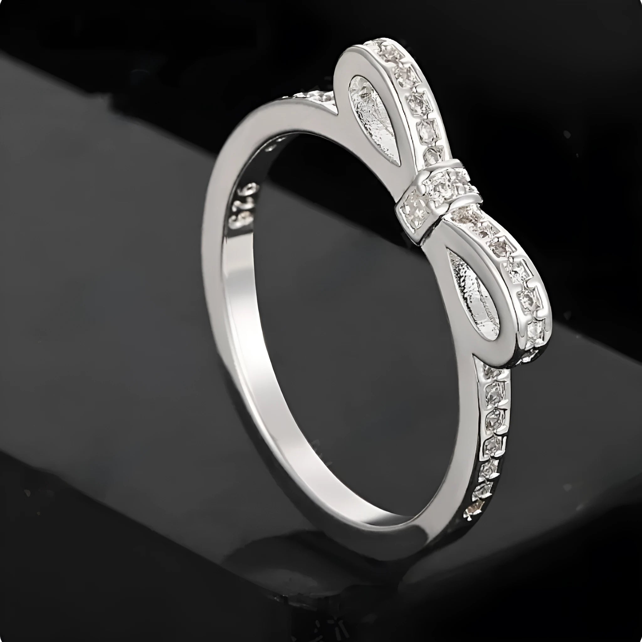 Silver electroplated ring with a detailed bow shape and set zircon crystal accents.