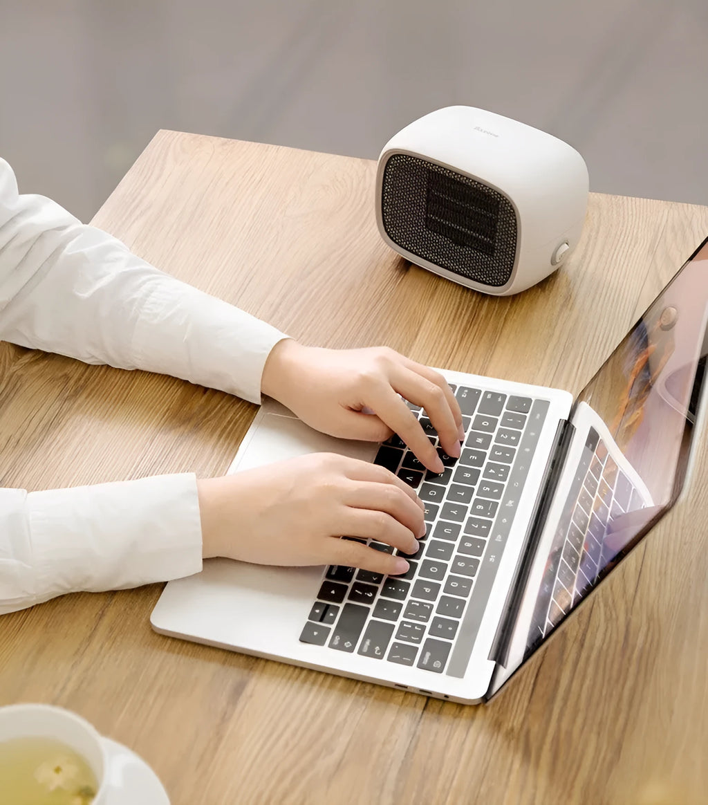 Compact green mini ceramic heater with metal mesh front on a wooden desk