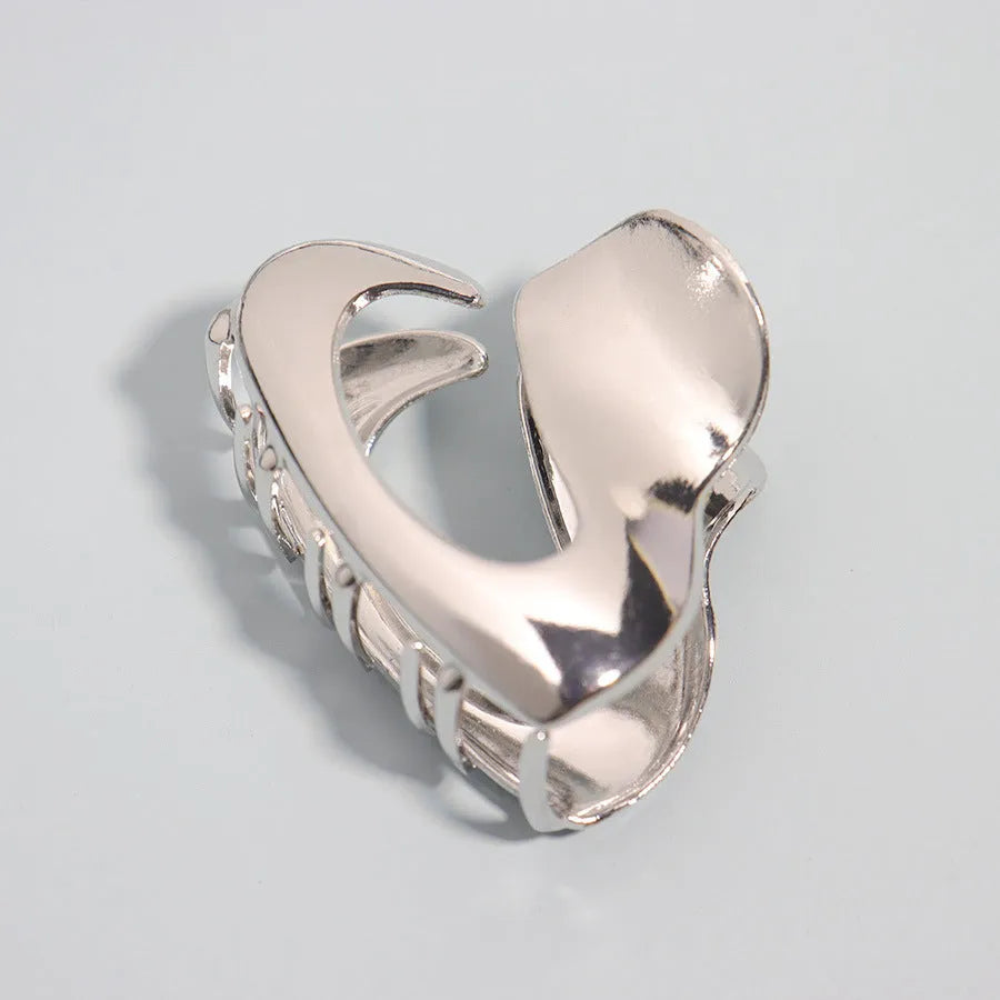 Assorted silver metal hair claws and barrettes including wave, knot, bow, and pearl designs on a white background.