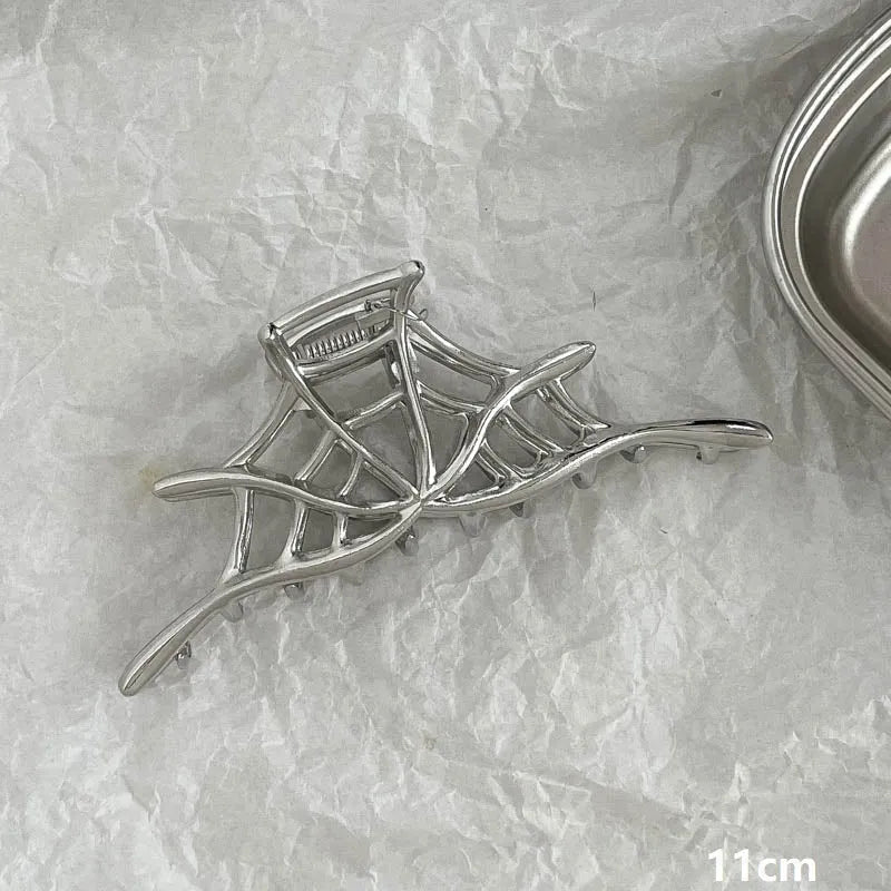 Assorted silver metal hair claws and barrettes including wave, knot, bow, and pearl designs on a white background.