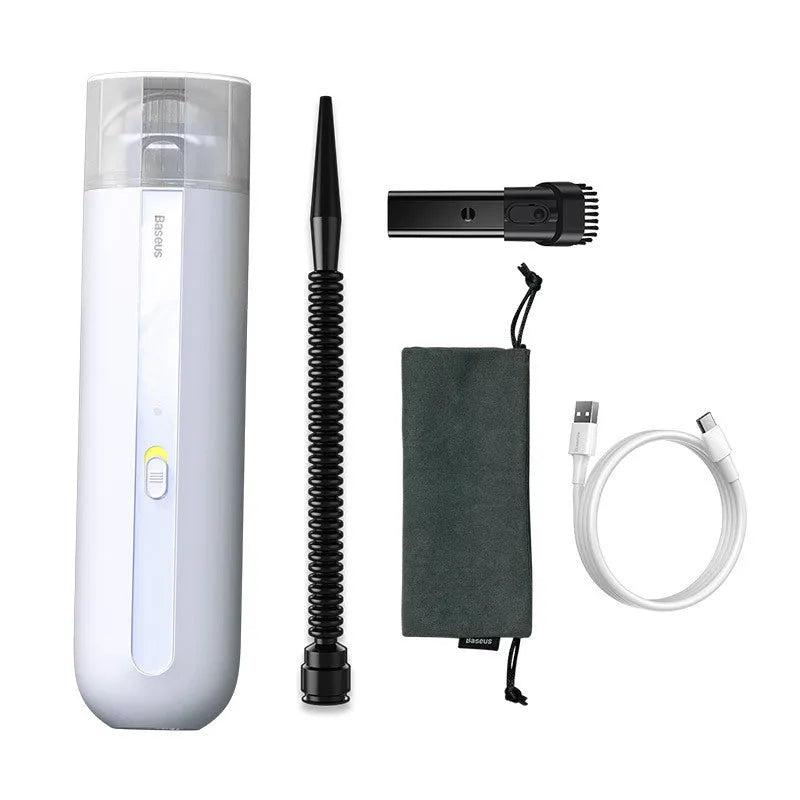 Black cordless handheld car vacuum cleaner with blowing hose attachment on a desktop.