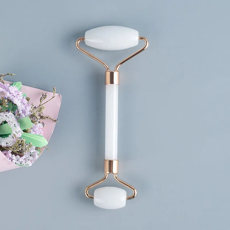 Natural white jade double-headed facial roller and gua sha scraping board set on a plain background.