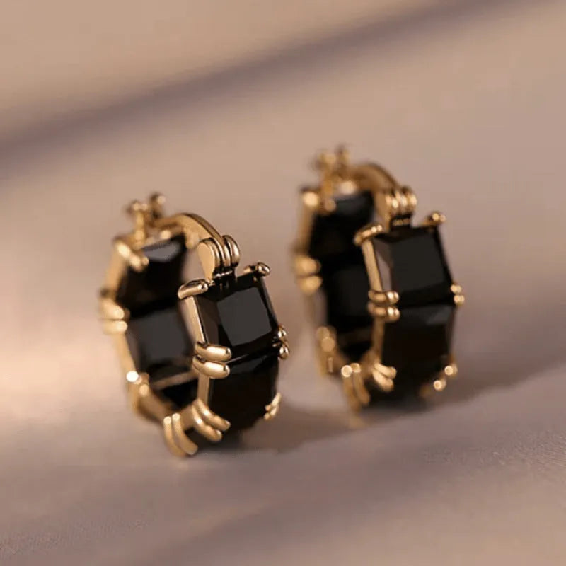 Geometric U-shaped gold-tone earrings with black zircon stones, approximately 20mm diameter
