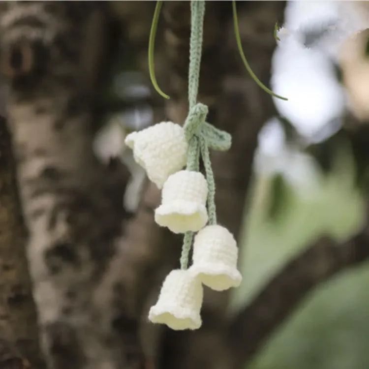 Green and white knitted wool car plant decoration with macramé texture and a white hanging rope.