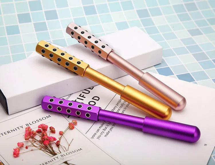Purple handheld facial massage roller with visible germanium beads on a rotating head