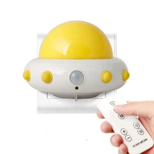 Blue UFO-shaped bedside night light with remote control on a wooden table.