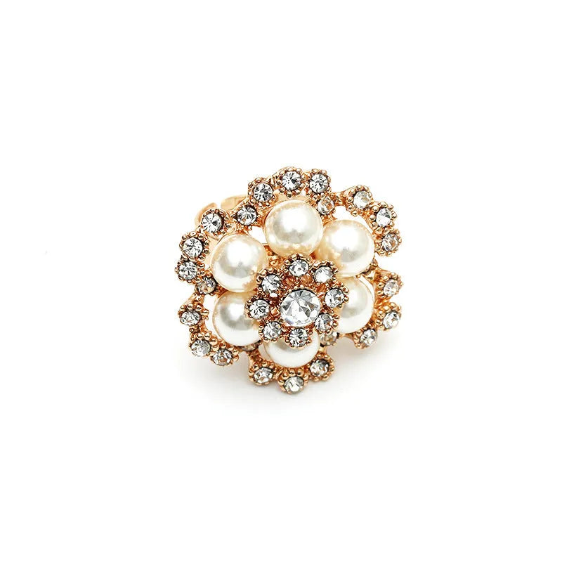 Simple retro fashion ring with pearl inlay and rhinestone flower shape in white KC gold on a flat surface
