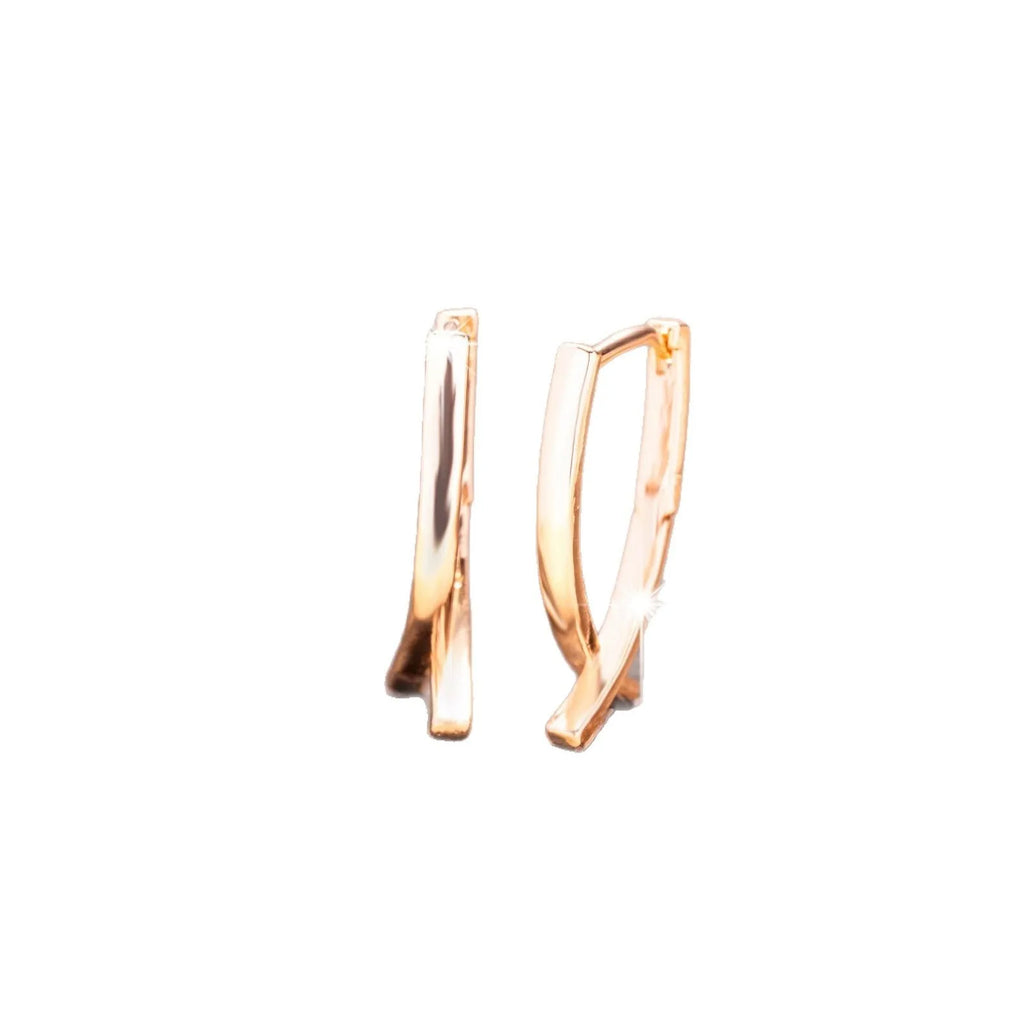 A pair of rose gold finished copper cross shaped drop earrings on a plain background.