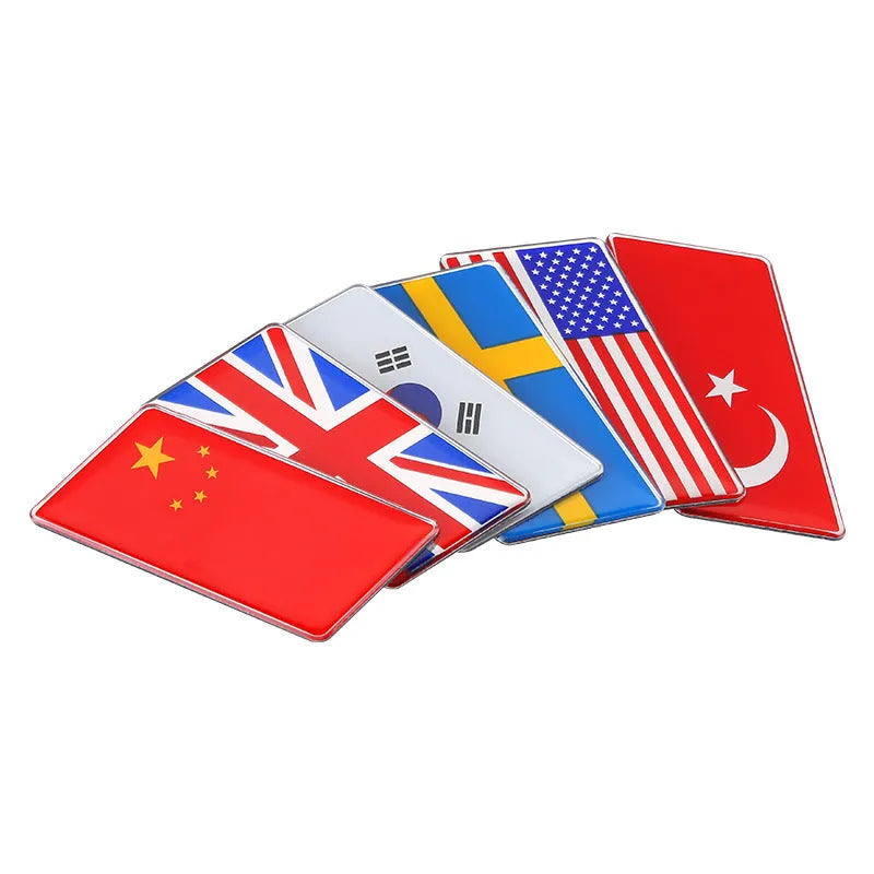 Aluminium parallelogram car sticker showing a national flag design, measuring 6.3 by 3 centimetres.