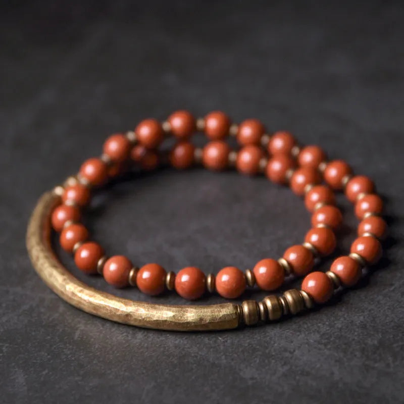 Layered retro ethnic bracelet with natural stone beads and antique brass details on a wrist.