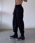 Men's plaid trousers with apron feature showing adjustable waistband and pocket details