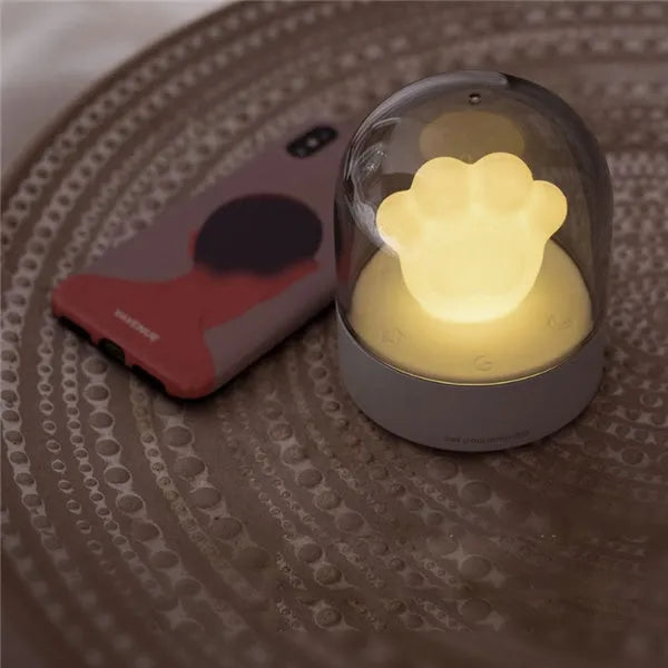 Grey or pink cat paw shaped USB rechargeable night light and music box on a desktop.
