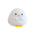 Cute duck-shaped silicone LED night lamp on a bedside table with warm light