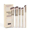 Angled apricot blusher brush and four other synthetic makeup brushes on a white surface.