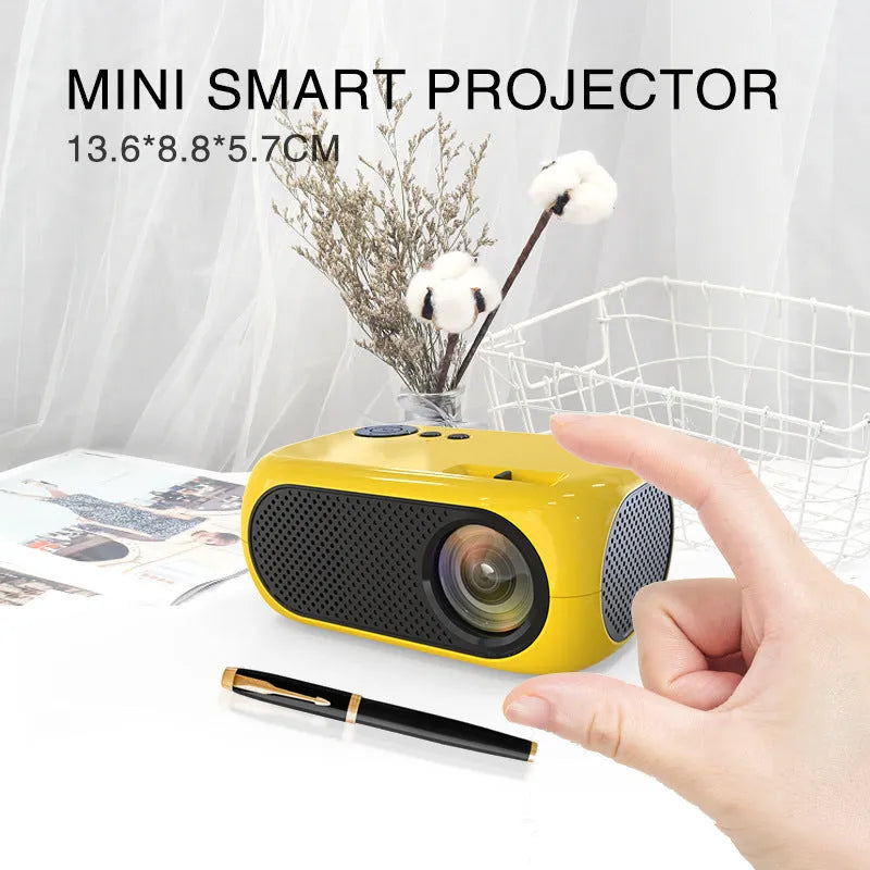M24 gold and white micro mini portable LED projector with power adapter and AV cable on a grey background