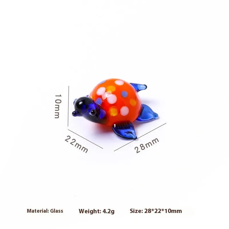 Geometric glass turtle ornament with a blue head and blue shell on a wooden desktop.