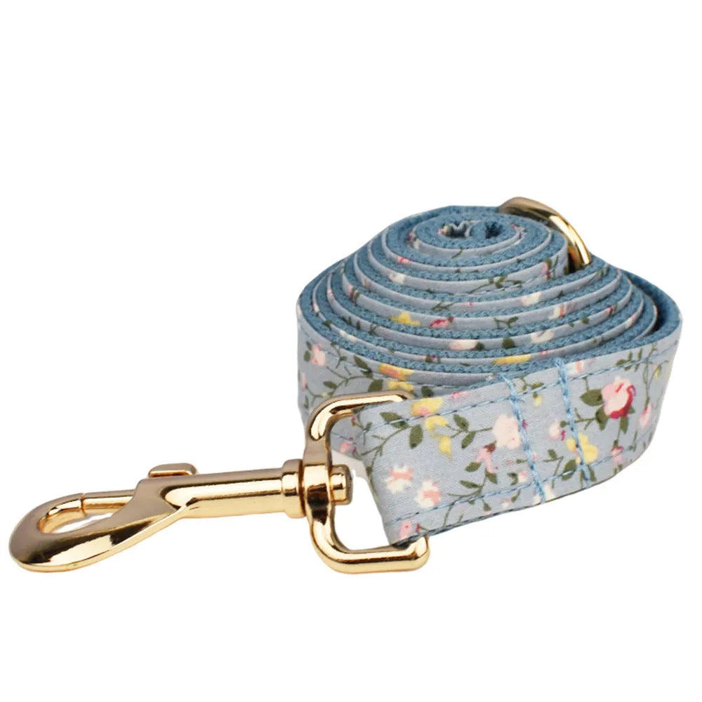 Blue floral patterned cloth dog collar and leash set with matching vest and bow accessories.
