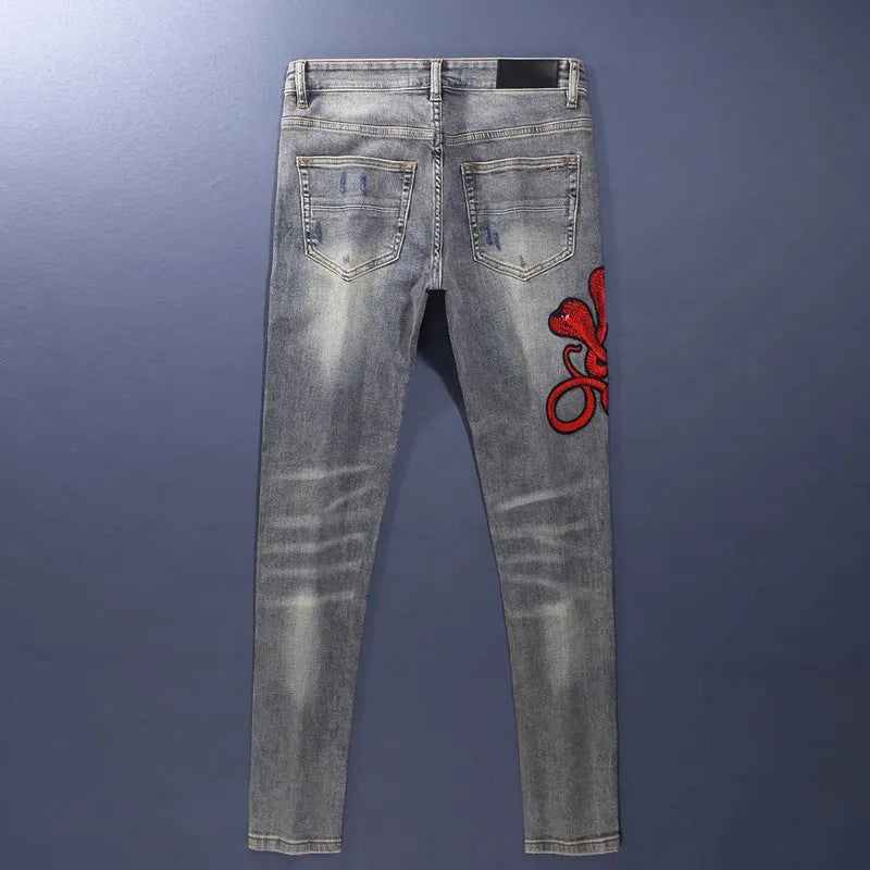 Distressed slim fit jeans with embroidered hole patches in washed-out old colour