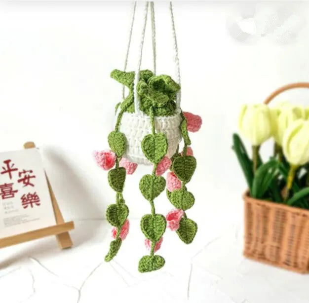 Green and white knitted wool car plant decoration with macramé texture and a white hanging rope.
