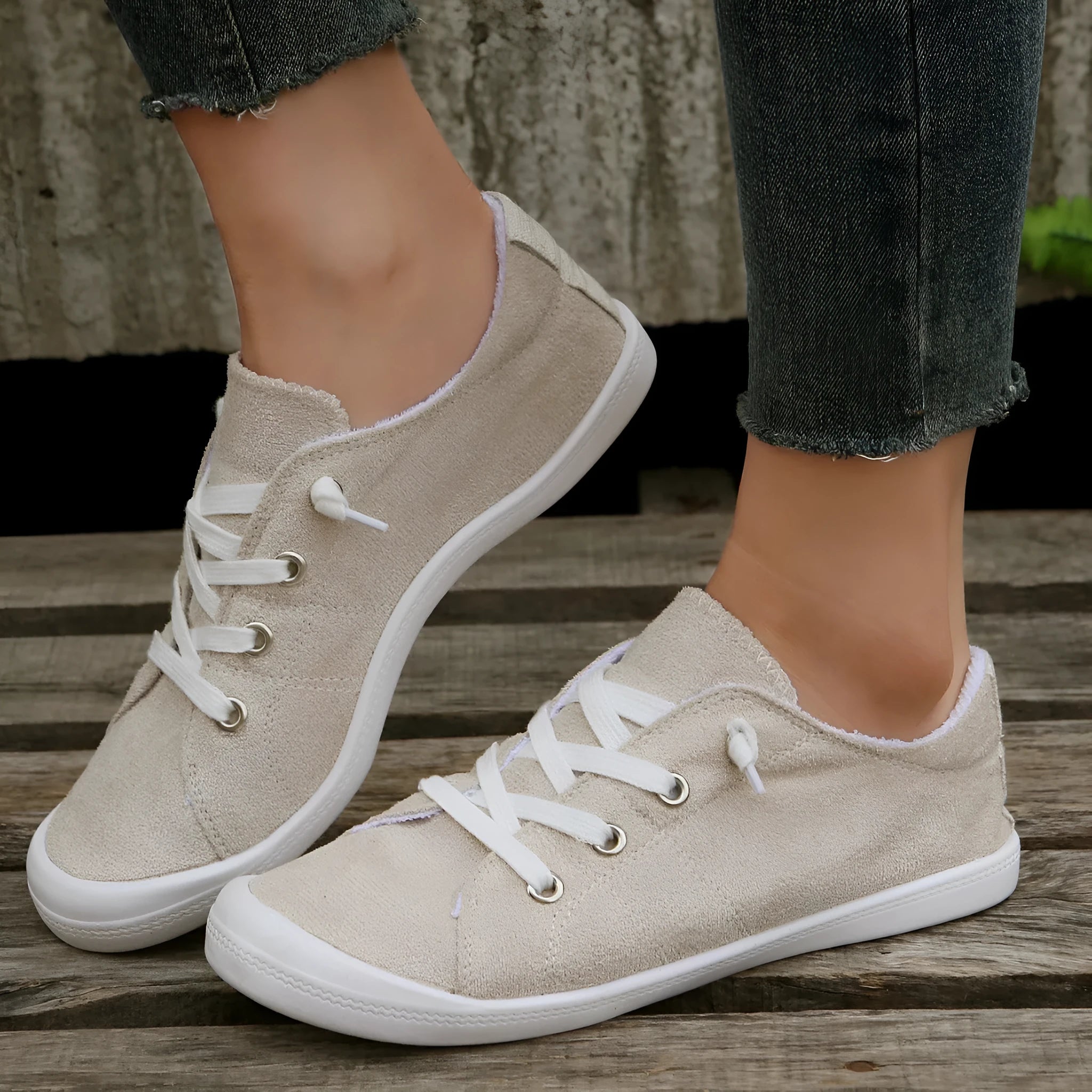 Women's creamy-white low-top fabric sneaker with rubber sole on a neutral background.