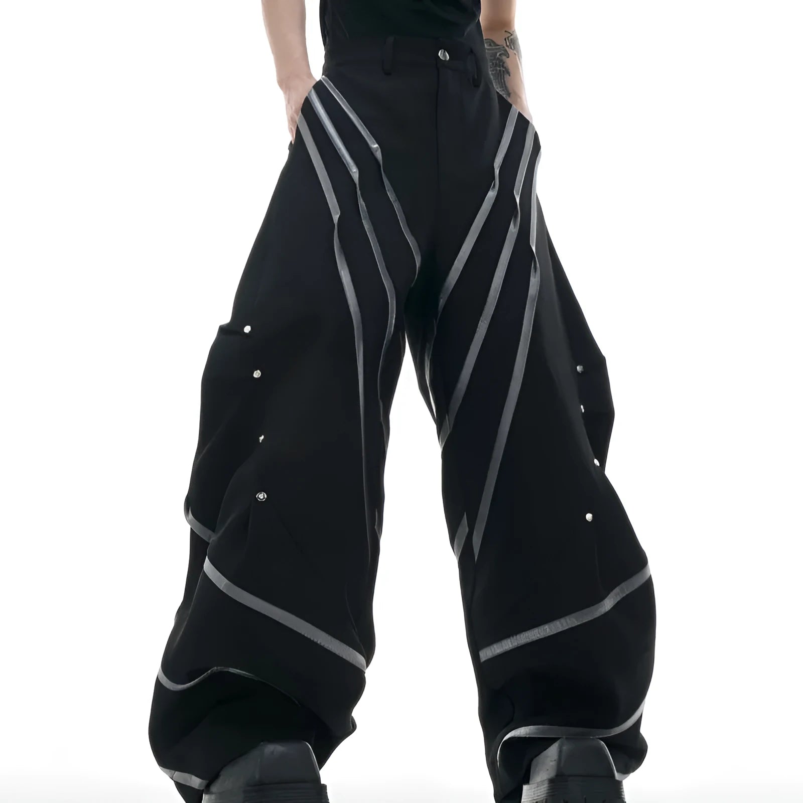 Men's black and white deconstructed trousers with metal striped rivets and front pleats.