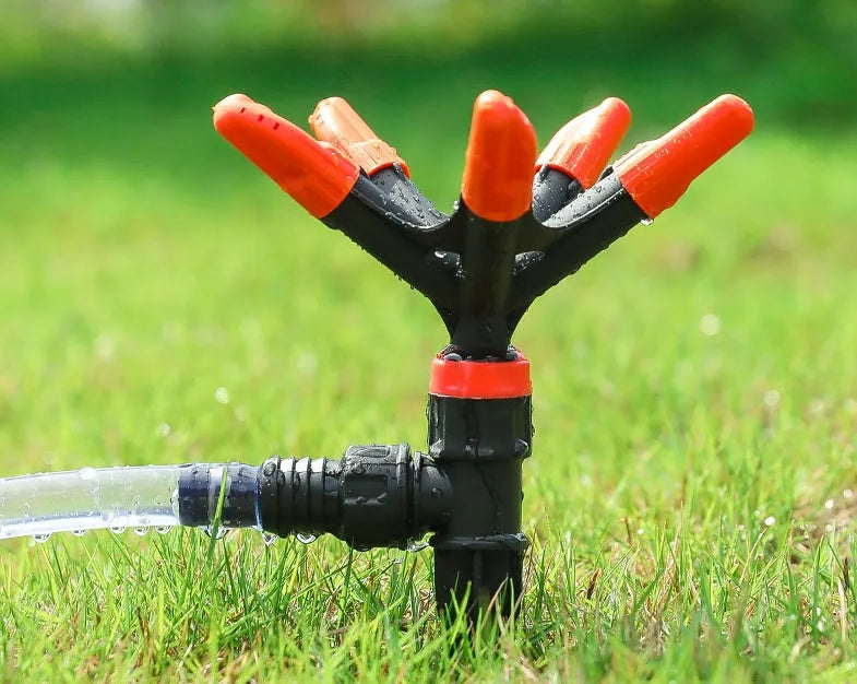 Automatic rotating garden sprinkler in orange plastic, size 14x26.5cm, on green lawn