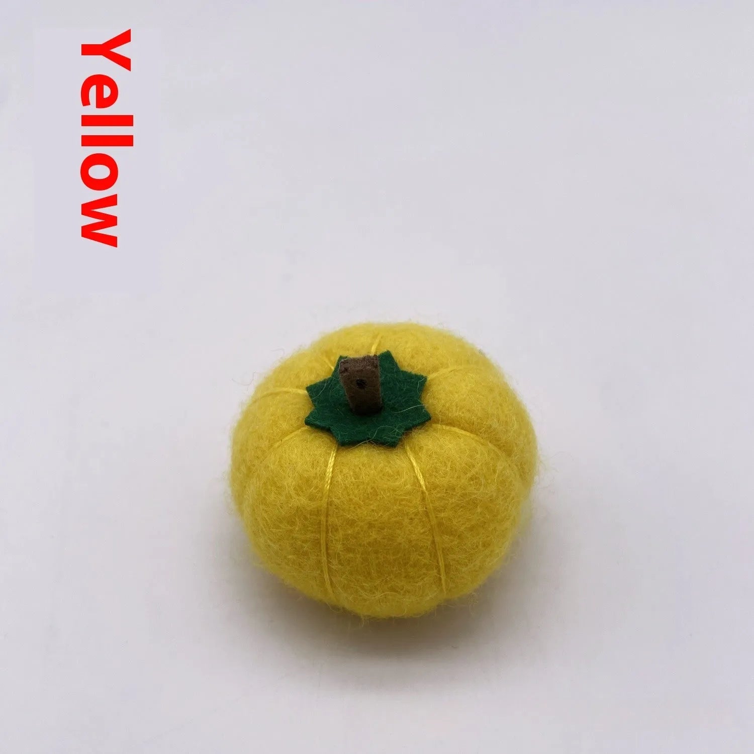 Wool felt pumpkin-shaped doll decorations in autumn colours on a neutral background