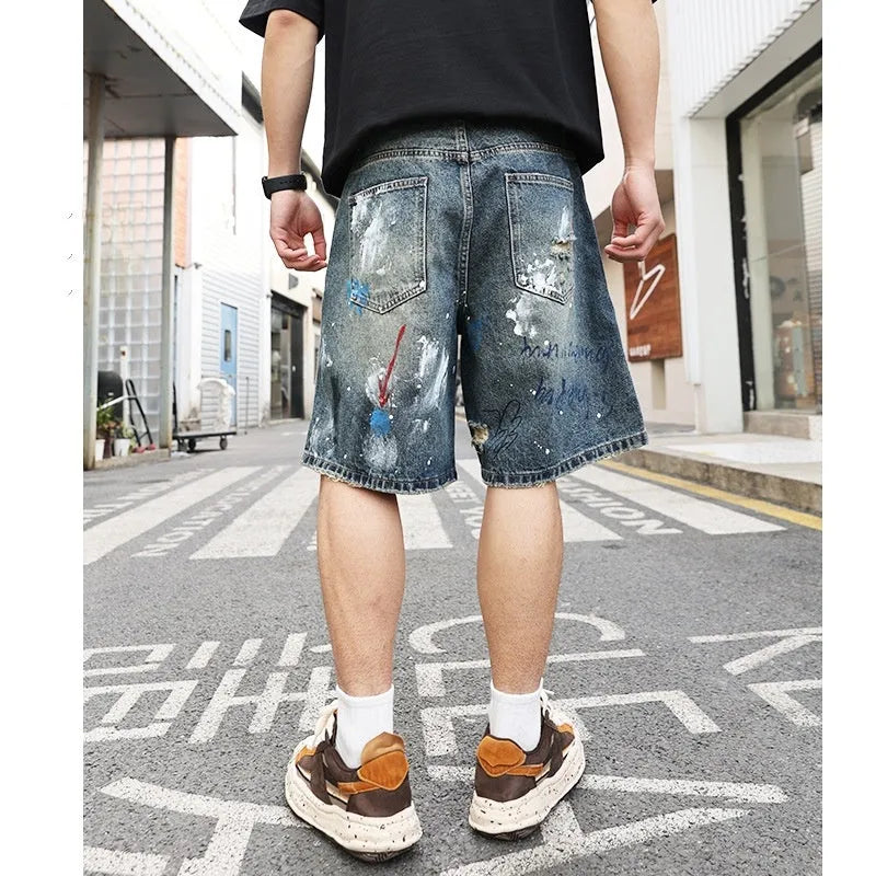 Men's blue ripped denim shorts with graffiti design and straight leg.
