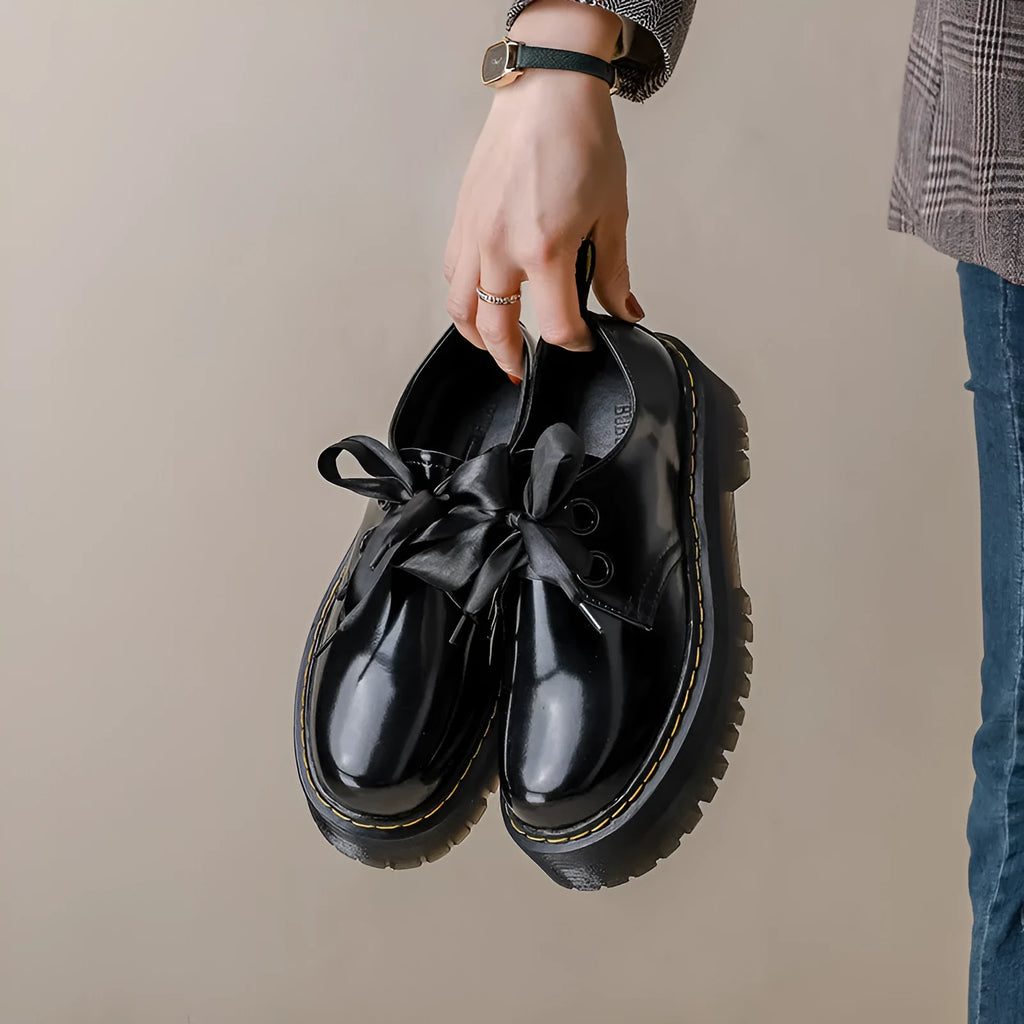 Women's black leather shoes with thick soles, ribbon cross straps, and lacing closure