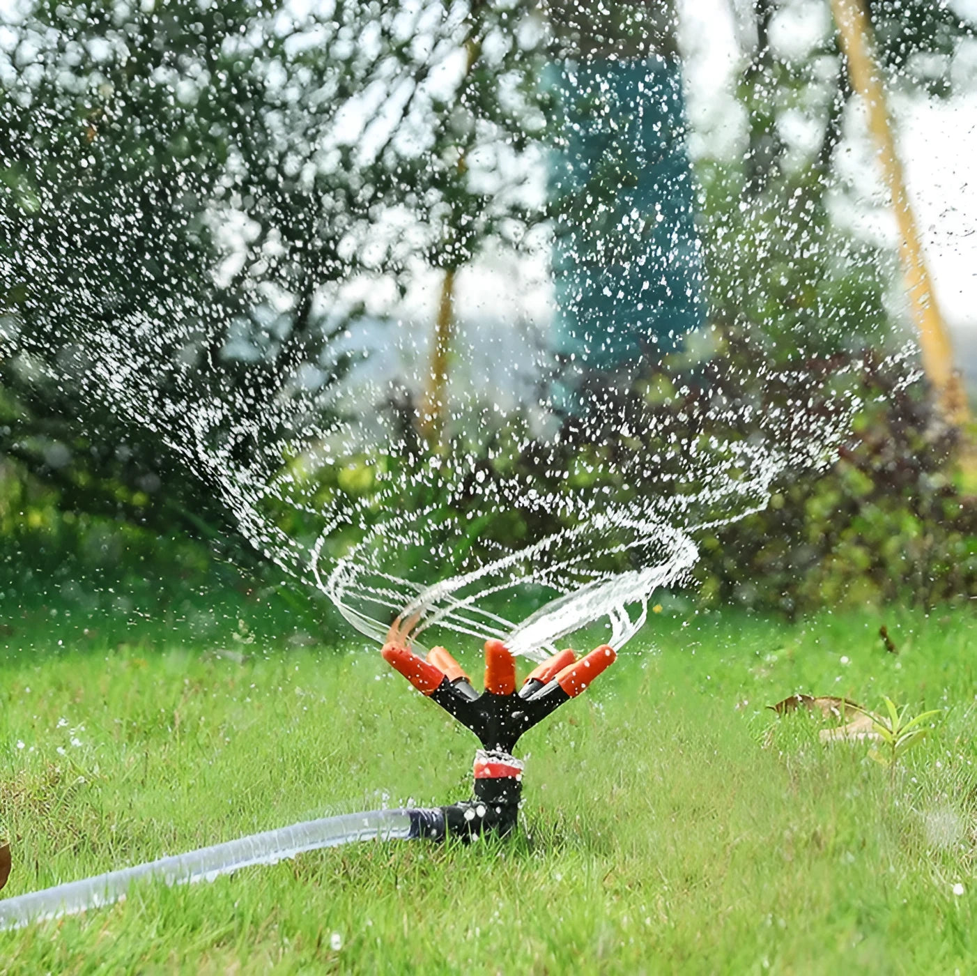 Automatic rotating garden sprinkler in orange plastic, size 14x26.5cm, on green lawn