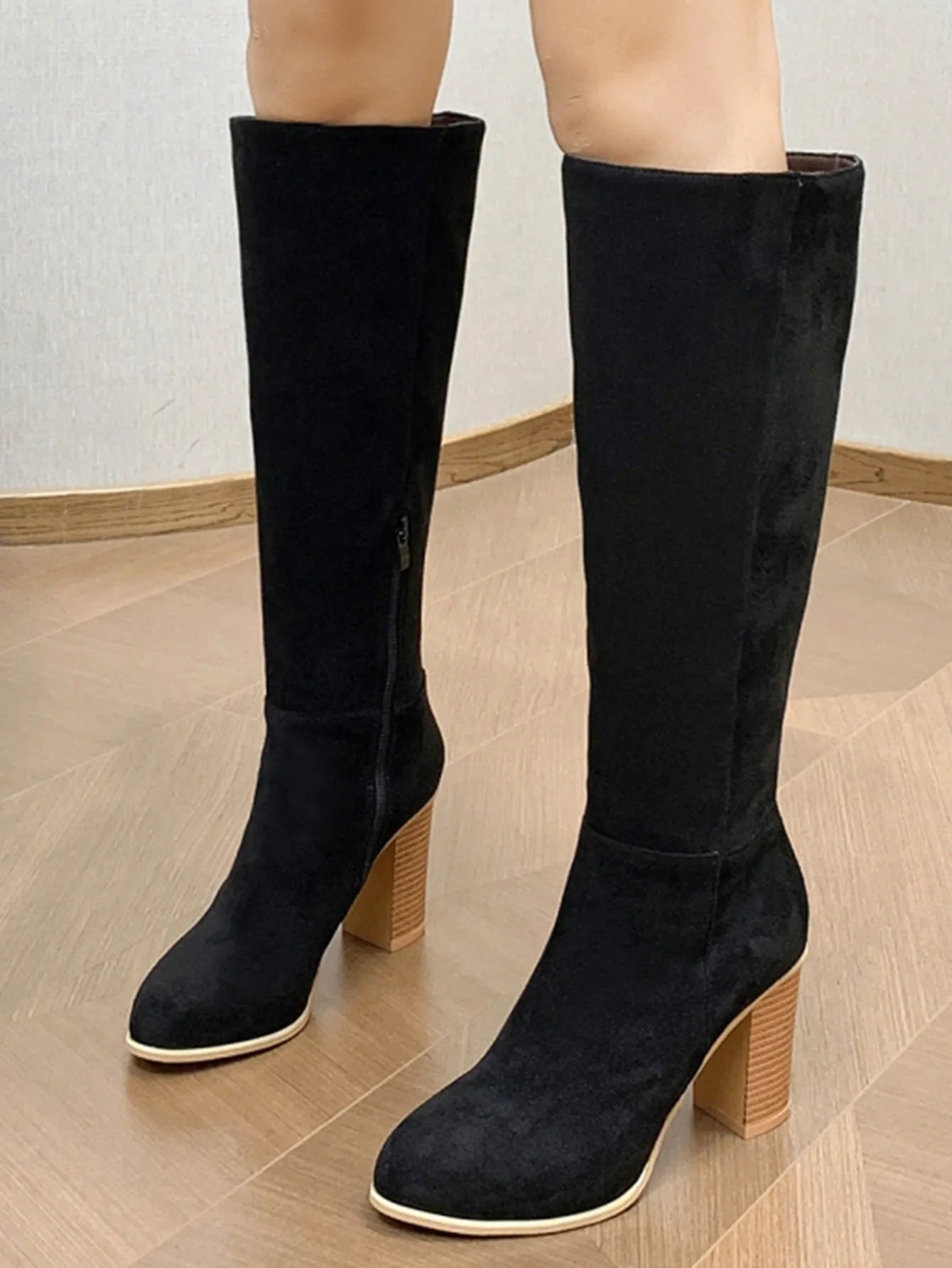 Black square toe high heel fashion boots for women on a plain background.