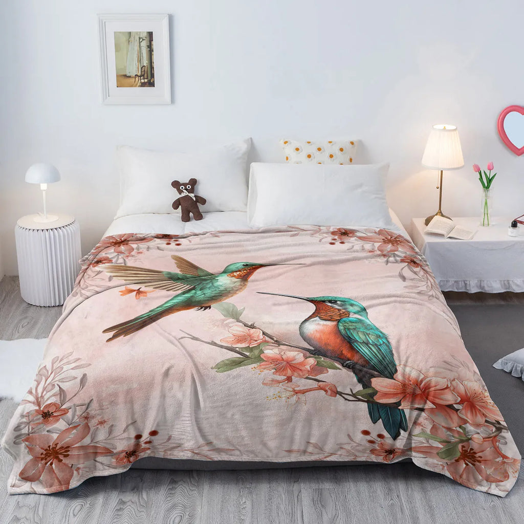 Hummingbird floral fleece throw blanket in pink flannel velvet, shown on sofa with hemmed edges
