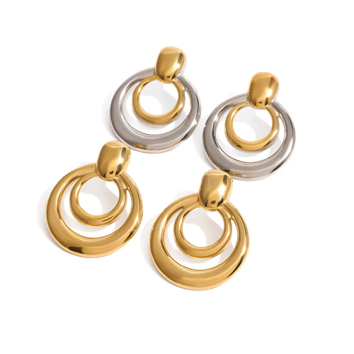 Close-up of a pair of round, geometric, double-layer hollow stud earrings with a golden electroplated finish.