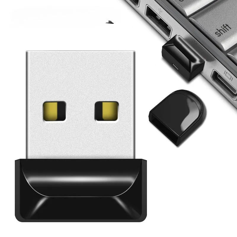 Silver car-shaped metal USB flash drive on a chain, shown next to a laptop.