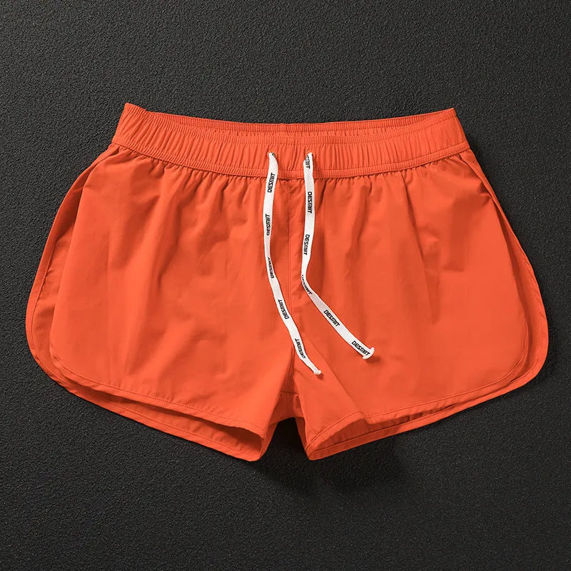 Man wearing loose orange red polyester beach shorts with elasticated waistband.