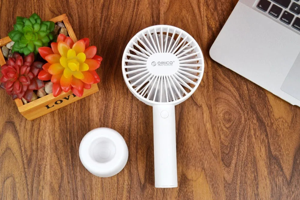 White ORICO FH1 handheld USB rechargeable desk fan with three-speed control on a desk.