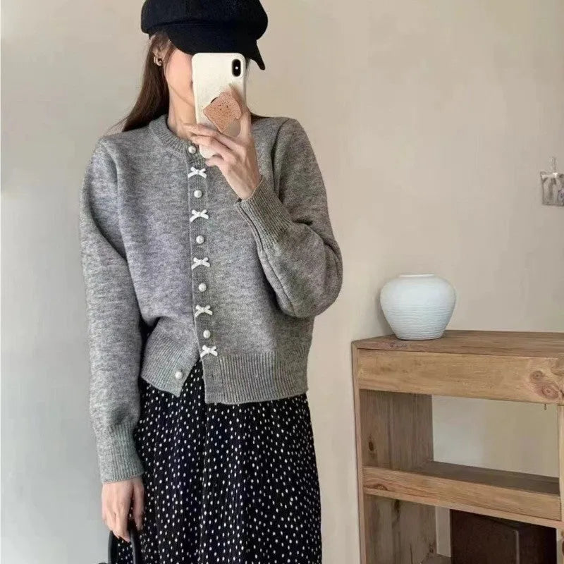 Women's solid colour cardigan with bow and pearl buttons, cashmere acrylic blend, shown in multiple colour options.