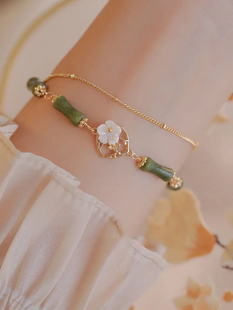 Natural olivine gemstone bracelet with double layers and twin Bells of Ireland charms on a wrist.