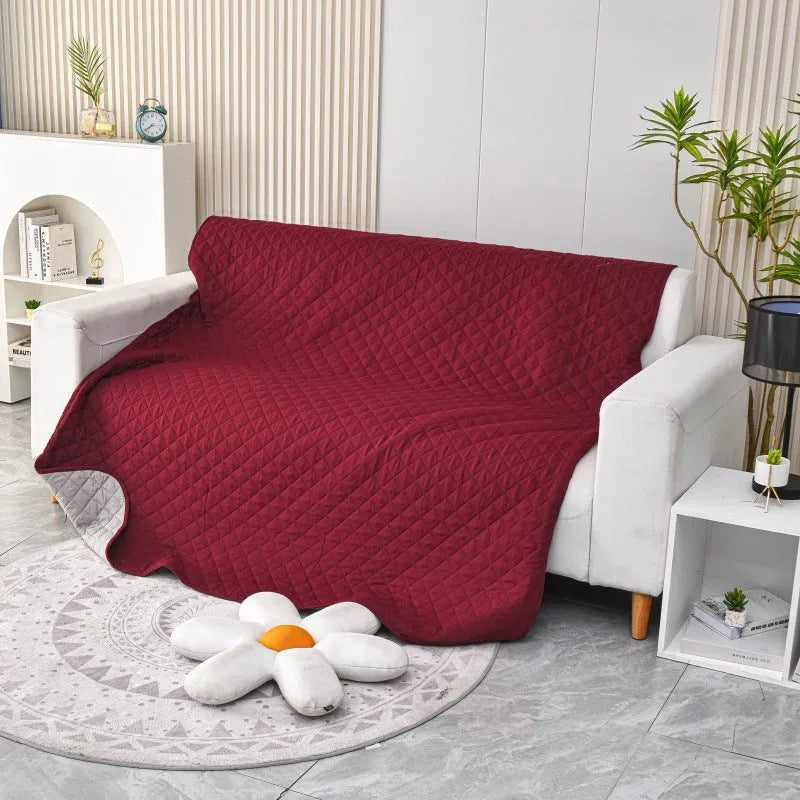 Reversible grey and burgundy waterproof dog blanket laid flat on a sofa.