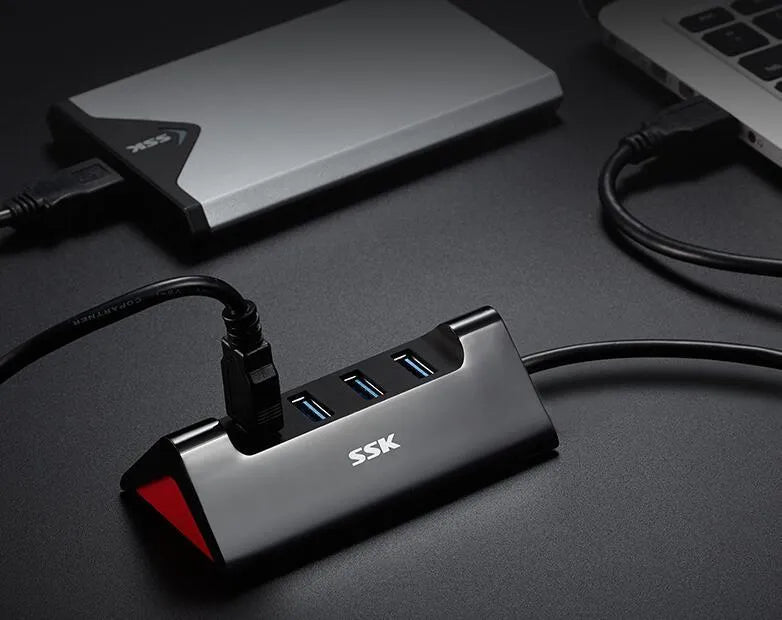 Black USB expansion dock with 4 ports and a Micro USB power input on a desk.