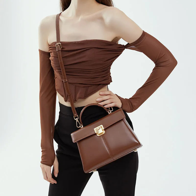 Women's black leather shoulder bag with vachette clasp showing internal compartments and adjustable strap